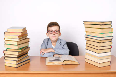 Education concept. A student with glasses sits at a table with books on both sides.の写真素材