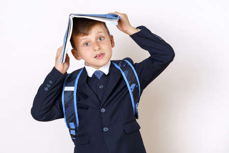 Education concept. The student holds a book on his head, looks at the camera. Isolated on white background.の写真素材