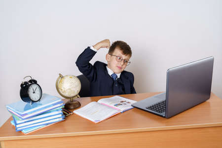 Education concept. The student has done homework and expresses emotions of joy. Books, a globe and pencils are on the table. Isolated on white background.の写真素材