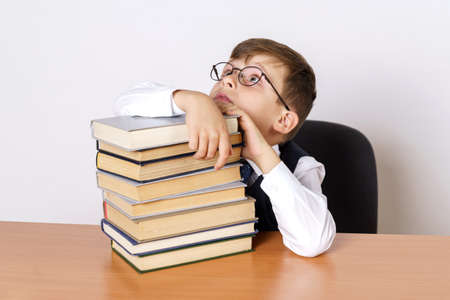 Education concept. The student sits at the table and holds his head, hands operate on the stacked...