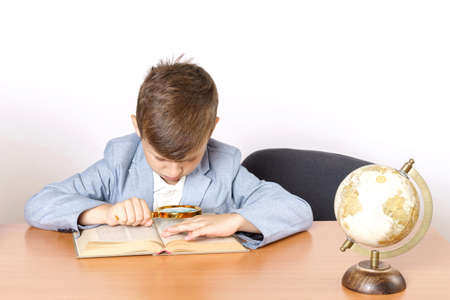 Education concept. The student does homework, reads a book with a magnifying glass.