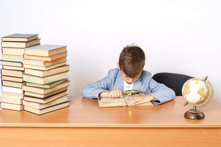 Education concept. The student does homework, reads a book with a magnifying glass.の写真素材