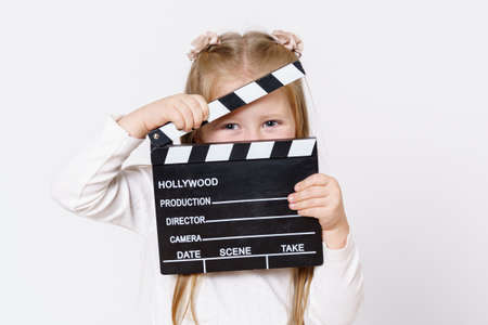 Children concept. A girl looks through a clapperboard into the camera. Isolated over white...