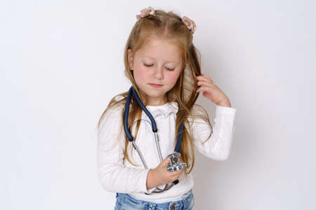 Medicine concept. A girl holds a stethoscope in her hands, plays with it. Isolated over white background.の写真素材