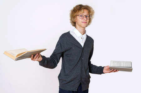 Education concept. Teen boy holding books in his hands and looking at the camera. Isolated over...