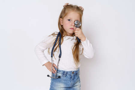 Medicine concept. A girl holds a stethoscope in her hands, plays with it. Isolated over white background.の写真素材