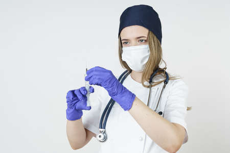Medicine and health concept. Young woman doctor prepares a syringe with medicines for injection. Isolated over white background.の写真素材