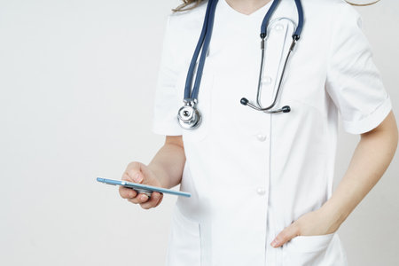 Medicine and health concept. Young woman doctor message in mobile phone. Isolated on white background.の写真素材
