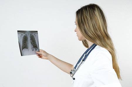 Medicine and health concept. A young woman doctor examines an x-ray picture of human chest. Isolated...