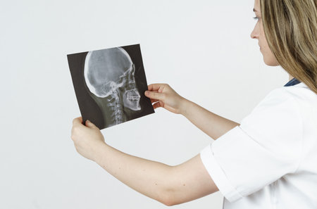Medicine and health concept. Young woman doctor examines an x-ray of the human skull. Isolated on...