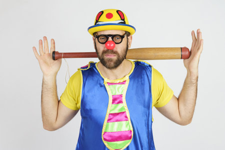 Holiday concept. The clown is a man in a bright blue and yellow suit with a baseball bat.