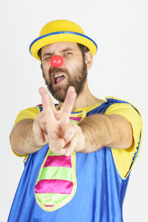 Holiday concept. A clown in a bright blue and yellow suit shows a slingshot with his hands - aimsの写真素材