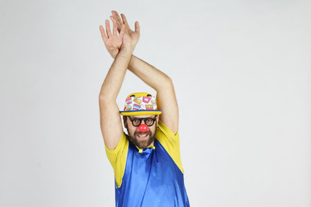 Holiday concept. The clown is a man in a bright blue and yellow suit, glasses and a hat, playing...