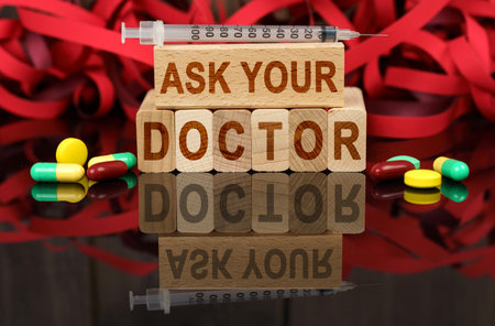 Medicine and health concept. On the surface are visible tablets, a syringe, wooden dies and their reflections on which it is written - ASK YOUR DOCTORの写真素材