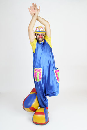 Holiday concept. The clown is a man in a bright blue and yellow suit, glasses and a hat, playing...