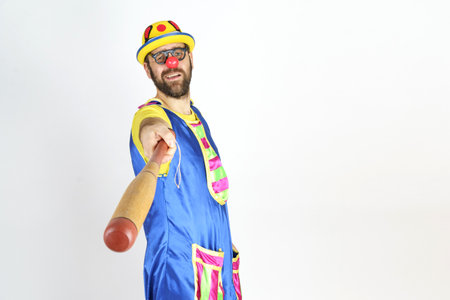 Holiday concept. The clown is a man in a bright blue and yellow suit with a baseball bat.