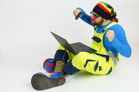 Celebration and communication concept. A clown in bright clothes sits on the floor and aggressively...