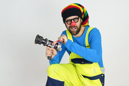 Holiday and fun concept. The clown firefighter holds a fire barrel in his hands, extinguishes the fire.の写真素材