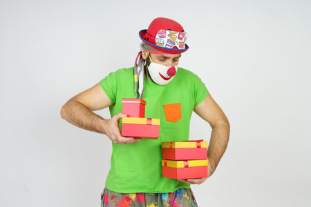 Holiday and fun concept. The clown holds gifts in his hands. Isolated on white