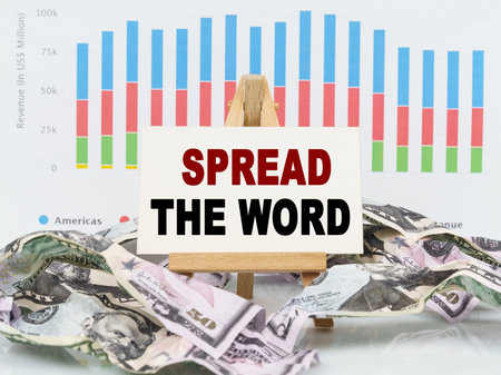 Business and finance concept. Among financial charts and money is a sign with the text - SPREAD THE WORDの写真素材