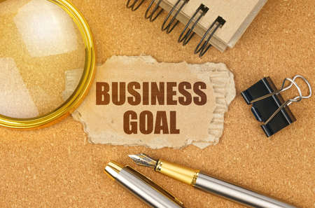 Business and finance concept. On the table are office items and a cardboard with the inscription - BUSINESS GOALの写真素材
