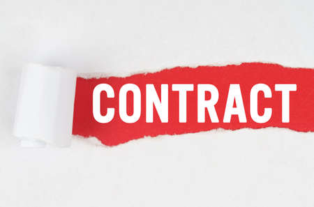 Business and finance. Behind torn white paper on a red background, the text - CONTRACT