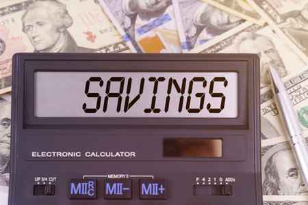 Business and finance concept. On the table are dollars and a calculator on the electronic board which says SAVINGSの写真素材