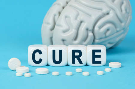 Medicine and health. Cubes lie on the table among the pills and imitation of the brain. The text on the dice - CUREの写真素材