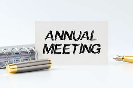 Business and finance concept. On the table is a notebook, a pen and a business card with the inscription - ANNUAL MEETINGの写真素材