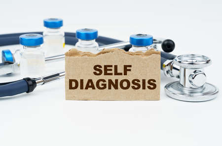 Medicine and health concept. On a white table lie ampoules, a stethoscope and a cardboard with the inscription - SELF DIAGNOSISの写真素材