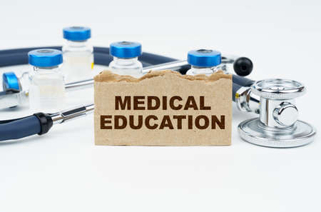 Medicine and health concept. On a white table lie ampoules, a stethoscope and a cardboard with the inscription - MEDICAL EDUCATIONの写真素材