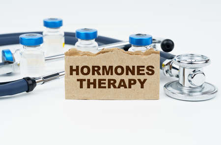 Medicine and health concept. On a white table lie ampoules, a stethoscope and a cardboard with the...