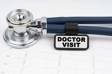 Medicine and health concept. On the cardiogram is a stethoscope and a plate with the inscription -...