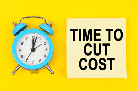 Business and finance concept. On a yellow background lie a clock and a sticker sheet with the...