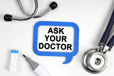 Medicine concept. On the table is a stethoscope, a marker and a sign with the inscription - ASK YOUR DOCTORの写真素材