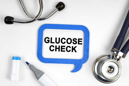 Medicine concept. On the table is a stethoscope, a marker and a sign with the inscription - GLUCOSE CHECKの写真素材