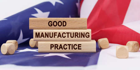 Business concept. The American flag has wooden cubes and plaques that say - GOOD MANUFACTURING PRACTICEの写真素材