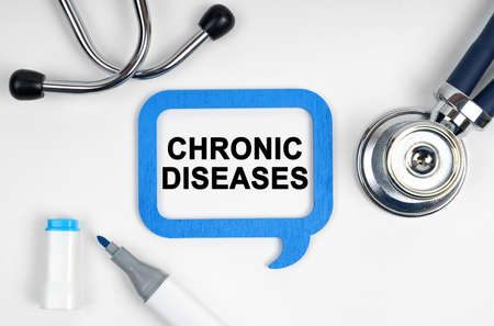 Medicine concept. On the table is a stethoscope, a marker and a sign with the inscription - CHRONIC DISEASESの写真素材