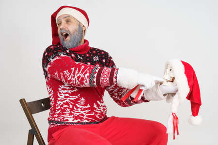 Holiday and Christmas concept. Santa Claus holds a skull in his hand. The skull bit Santa's finger.