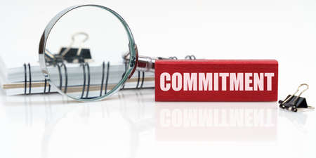 Business concept. On the table is a notebook, a magnifying glass and a tablet with the inscription - COMMITMENTの写真素材
