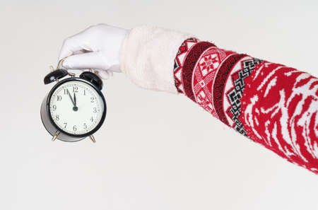 Holiday and Christmas concept. Santa Claus points to the clock before Christmas. Santa hat on the clockの写真素材