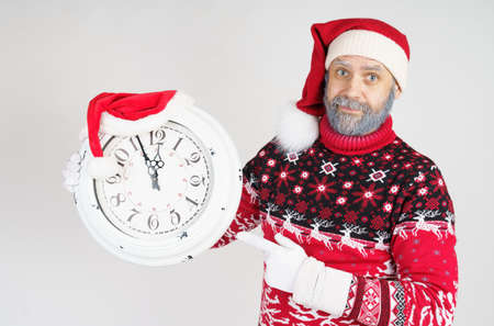 Holiday and Christmas concept. Santa Claus points to the clock before Christmas. Santa hat on the...