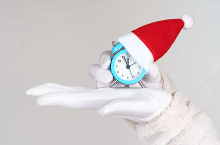 Holiday and Christmas concept. Santa Claus holds an alarm clock in his palm.