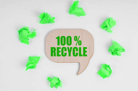 Ecology concept. On a white background, there are crumpled green pieces of paper and a wooden sign with the inscription - 100 Recycleの写真素材