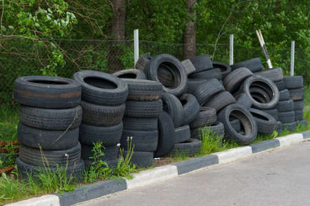 Ecology concept. Dump of old car tires near the forest