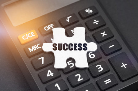 Business and finance concept. There is a white puzzle on the calculator with the inscription - SUCCESSの写真素材