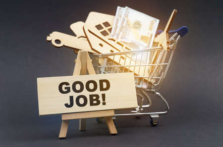 Business and finance concept. On a black background, there is a shopping cart with purchases, next to an easel and a sign with the inscription - GOOD JOBの写真素材