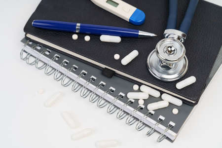 Medicine and health concept. On the table are a notebook, a stethoscope, a pen, pills and a...
