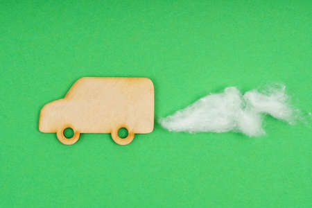 Environmental concept. Wooden lorry with traces of CO-2 emissions - cotton wool. Isolated on a green background.の写真素材