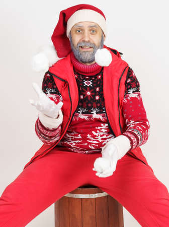 Christmas and New Year concept. Santa Claus sits on a barrel and plays with snowballs.の写真素材
